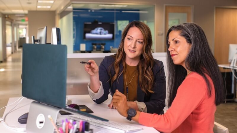 two colleagues talking at a desk